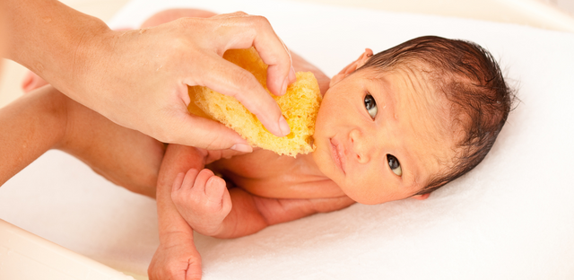 Imagen de un bebe siendo bañado.