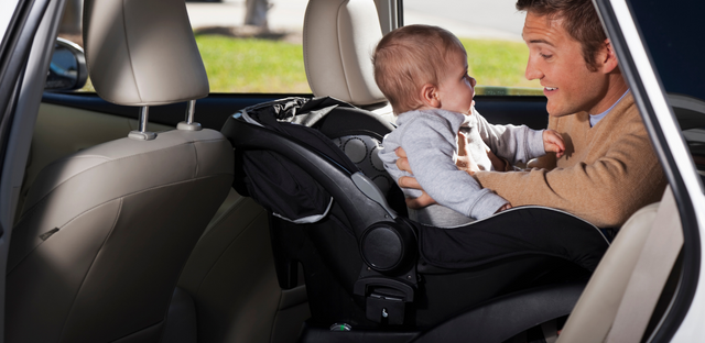 Padre acomodando a bebe en asiento protector.