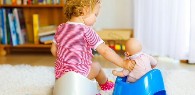 Imagen de una niña jugando con su muñeca simulando " potty trained"