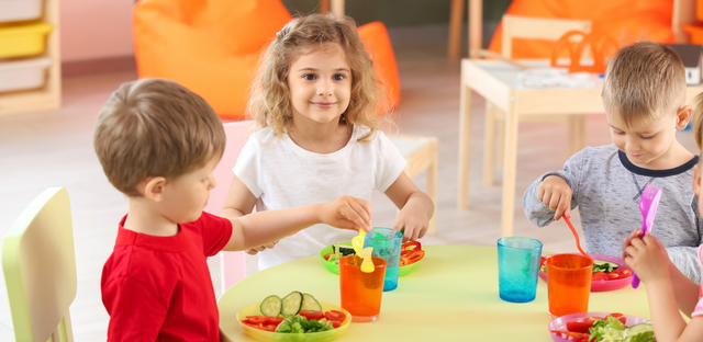 Imagen de un grupo de niños comiendo en una mesa redonda.