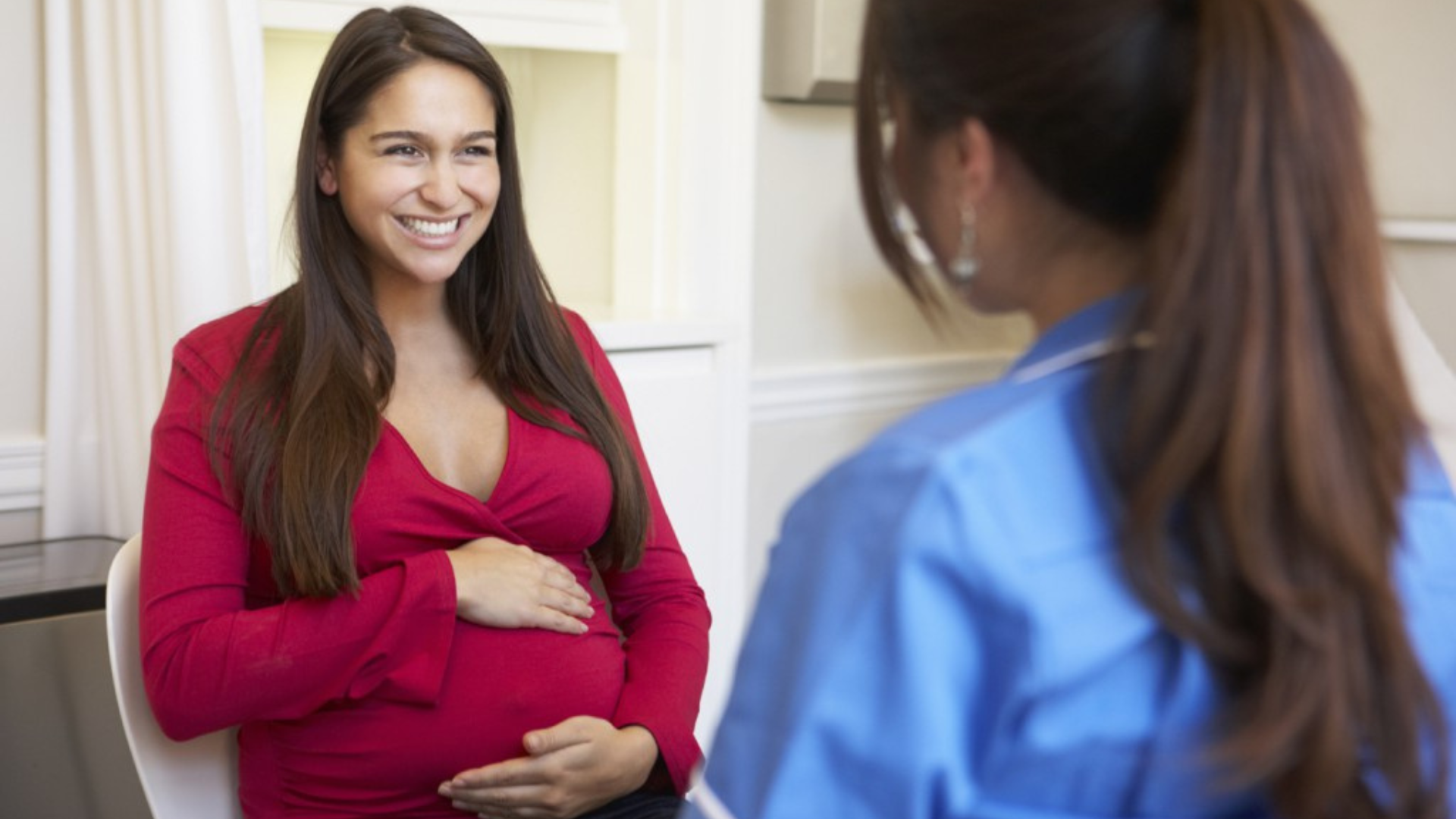 Mujer embarazada charlando con otra mujer.